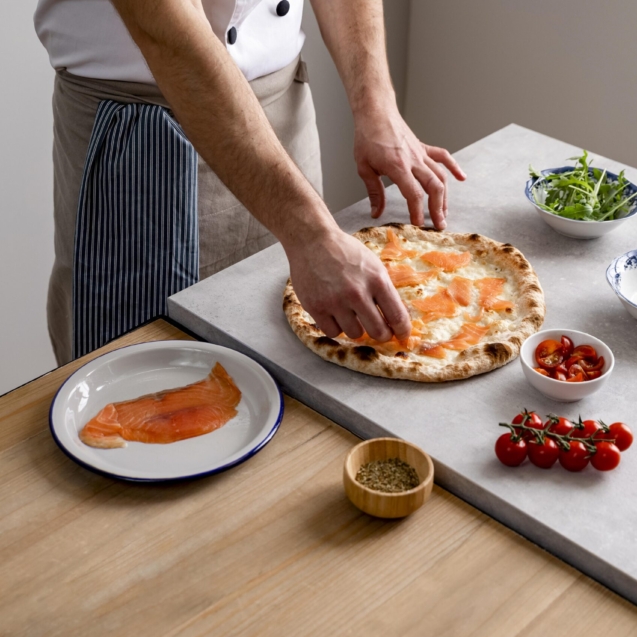 hombre-alto-angulo-poniendo-rodajas-salmon-ahumado-sobre-masa-pizza-al-horno