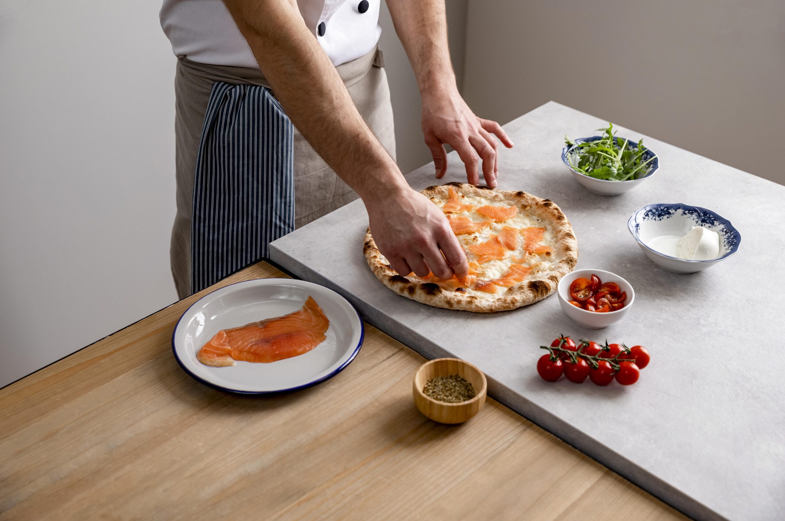 hombre-alto-angulo-poniendo-rodajas-salmon-ahumado-sobre-masa-pizza-al-horno