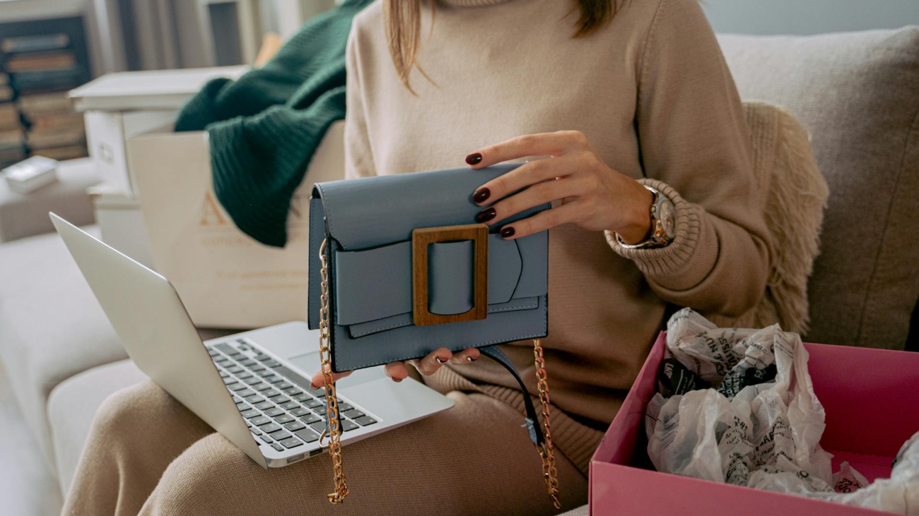 Se ve una mujer con un bolso y un ordenador. Representa que está comprando online.