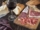 Una mesa con vino, fuet, pan y jamón serrano. Representa los alimentos típicos de españa. Hace alusión a las denominaciones de origen.