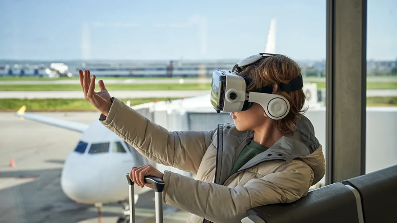 Una niña en un aeropuerto con unas gafas de realidad virtual. Parece ser una analogía entre el turismo virtual (que hace con las gafas) y el real (que se manifiesta con el aeropuerto).